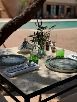 a table with plates and glasses on top of it at Le mas de l'Ourika, maison d'hôtes in Aït Zat