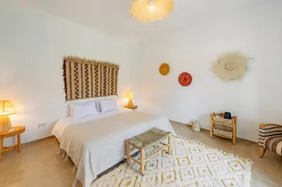 a bedroom with a large bed and a chandelier at Le mas de l'Ourika, maison d'hôtes in Aït Zat