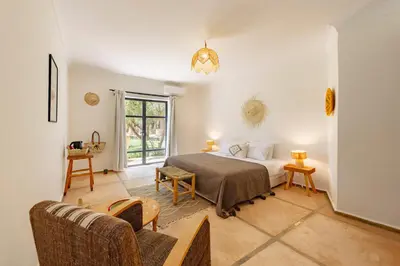 a bedroom with a bed and a couch at Le mas de l'Ourika, maison d'hôtes in Aït Zat