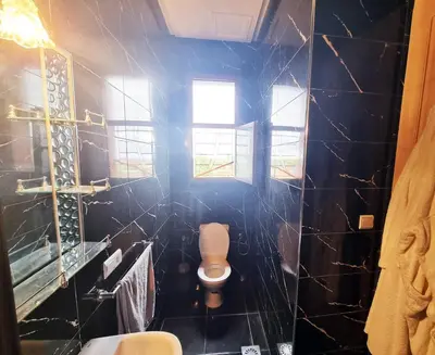 a bathroom with a toilet and a black tiled wall at Hotel&Restaurant Atlas Symphony in Ourika