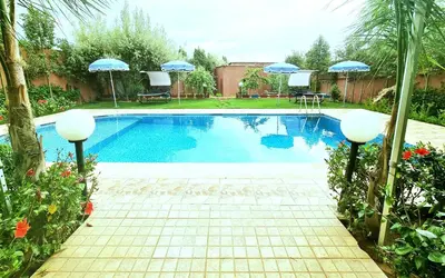 a swimming pool with umbrellas in a yard at Hotel&Restaurant Atlas Symphony in Ourika