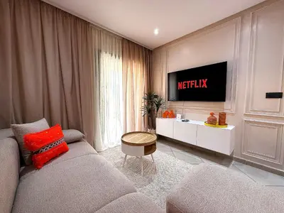 a living room with a couch and a tv on a wall at New appart moderne à Gueliz , charme et confort in Oulad Akkou