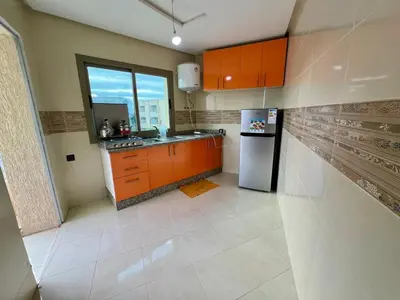 a kitchen with orange cabinets and a refrigerator at Residence Noor - Central Apartments Fes in Fès
