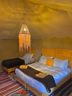 a bedroom with two beds and a chandelier at Desert Campo in Oulad Akkou