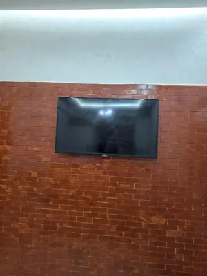 a flat screen tv on a brick wall at Apparemment pour vacances in Oulad Akkou