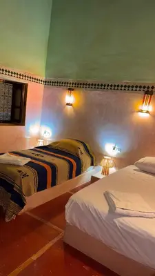 two beds in a room with lights on the wall at Hotel Kasbah Fenguig in Er Rachidia