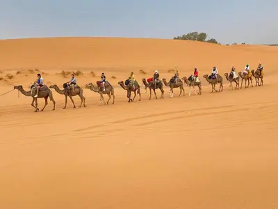 a group of people riding horses in the desert at Hotel Kasbah Fenguig in Er Rachidia