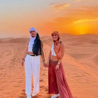 two women standing in the desert at sunset at Desert Bloom Luxury Camp in Merzouga