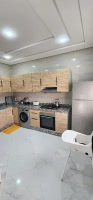 a kitchen with a refrigerator and a table and a chair at CHALEt VILLA PISCINE PRIVÉE in Imouzzer Kandar