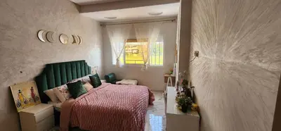 a bedroom with a bed with a green headboard and a window at CHALEt VILLA PISCINE PRIVÉE in Imouzzer Kandar
