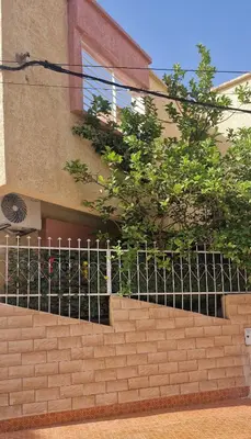 a brick wall with a fence in front of a building at Maison individuelle lazaret in Oulad Akkou