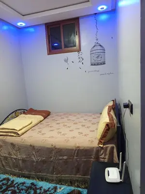 a bedroom with a bed and a bird cage on the wall at Farah in Oulad Akkou