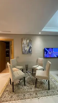 a living room with a table and chairs on a rug at Comfortable and charming apartment in Oulad Akkou