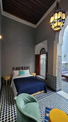 a bedroom with a large bed and a chair at Riad Dar Bahija Fes in Fès