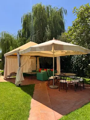 a patio with tables and chairs under an umbrella at Maison Dar Rima in Aït Ali Ou Allah