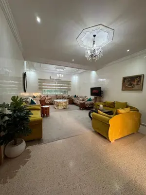 a large living room with yellow couches and a chandelier at Maison Dar Rima in Aït Ali Ou Allah