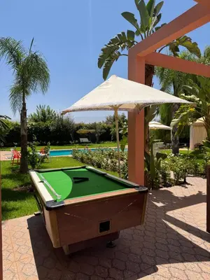 a pool table sitting on a patio with an umbrella at Maison Dar Rima in Aït Ali Ou Allah