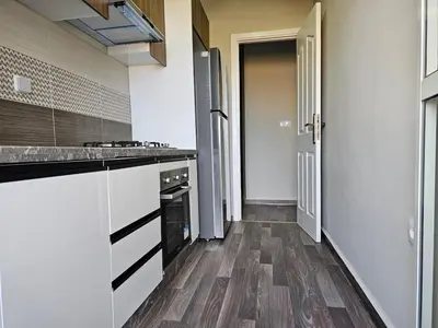 a kitchen with white cabinets and a wooden floor at Cosy appartement in Oulad Akkou
