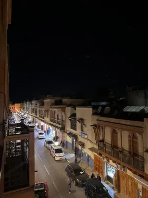 a city street at night with cars parked on the street at Dar Kenza in Fès
