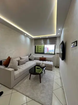 a living room with a white couch and a tv at Maison in Oulad Akkou