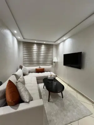 a living room with a white couch and a tv at Maison in Oulad Akkou