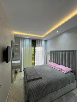 a bedroom with a bed with pink pillows and a television at Maison in Oulad Akkou