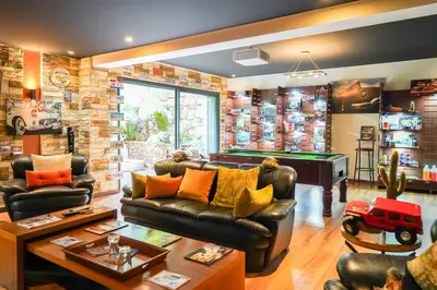a living room with a leather couch and a pool table at The Classic Affair For Car Lovers in Oulad Akkou