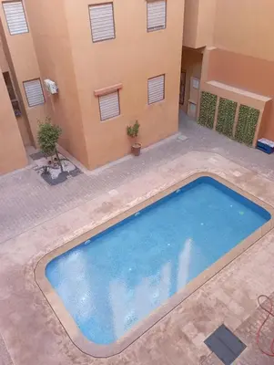 a large swimming pool in a courtyard with a building at Appartement Nour sakane targa kech in Oulad Akkou
