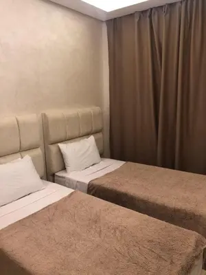 a bedroom with two beds and a curtain at Appartement Nour sakane targa kech in Oulad Akkou