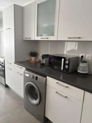 a kitchen with a washing machine and a microwave at Duplex confortable in Oulad Akkou
