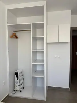 a white closet with white shelves and a appliance at Duplex confortable in Oulad Akkou