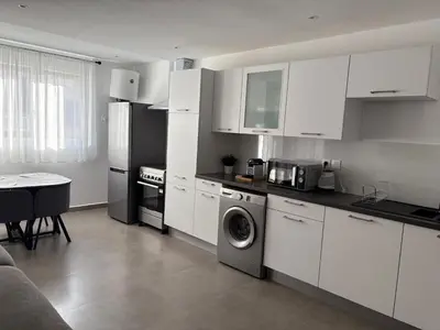 a kitchen with white cabinets and a washing machine at Duplex confortable in Oulad Akkou