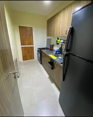 a kitchen with a black refrigerator and wooden cabinets at شقةبالقرب من مطار مراكش المنارة الدولي in Oulad Akkou