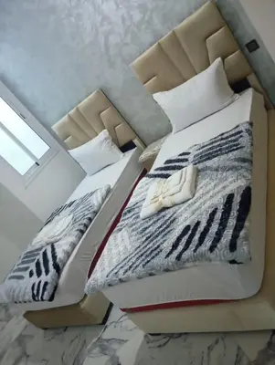 two twin beds in a room with a window at Appartement chic fes in Oulad Akkou