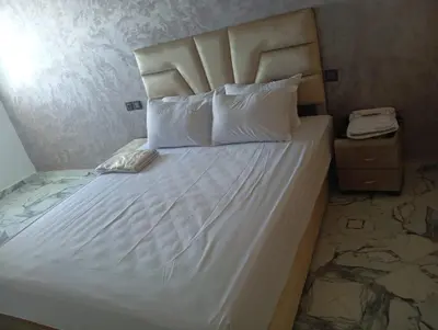 a bed with white sheets and pillows in a room at Appartement chic fes in Oulad Akkou