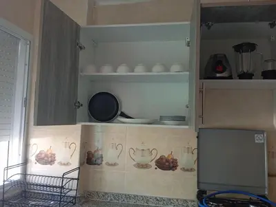a kitchen with white cabinets with bowls and plates at Appartement chic fes in Oulad Akkou