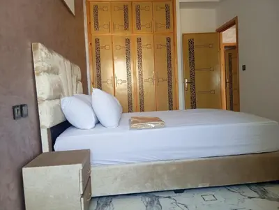 a bed with white pillows and a door in a room at Appartement chic fes in Oulad Akkou