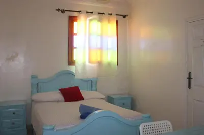 a bedroom with a blue bed and a window at Hotel Maison Olga in Meknès