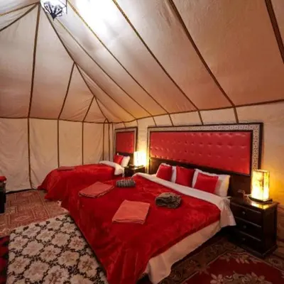 a bedroom with a red bed in a tent at Moha Luxury Camp in Merzouga