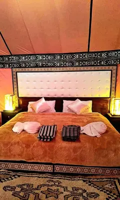 a bedroom with a large bed with two pillows at Moha Luxury Camp in Merzouga