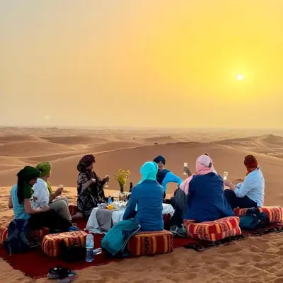 a group of people sitting around a table in the desert at Moha Luxury Camp in Merzouga