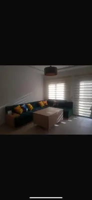a living room with a couch and two windows at Cosy appartement in Oulad Akkou