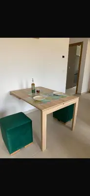 a wooden table in a room with a green stool at Cosy appartement in Oulad Akkou