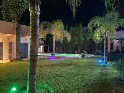 a yard with palm trees and lights at night at Villa Denalya in Marrakech