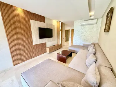 a living room with a couch and a tv on a wall at Appartement prestigia saphir in Oulad Akkou