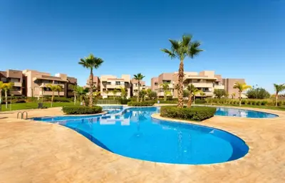 a swimming pool in a resort with palm trees at Appartement prestigia saphir in Oulad Akkou