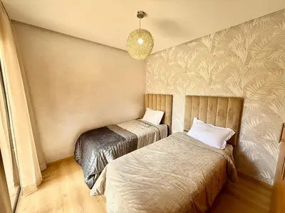 a bedroom with two beds and a chandelier at Appartement prestigia saphir in Oulad Akkou