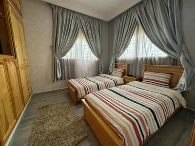 two beds in a room with two windows at Villa piscine espace vert luxueuse in Oulad Akkou