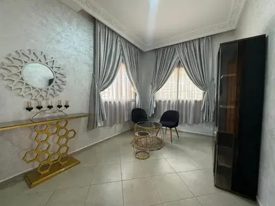 a living room with a mirror and a table and chairs at Villa piscine espace vert luxueuse in Oulad Akkou