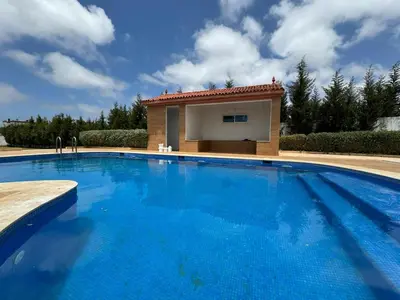 a large blue swimming pool with a building in the background at Villa piscine espace vert luxueuse in Oulad Akkou